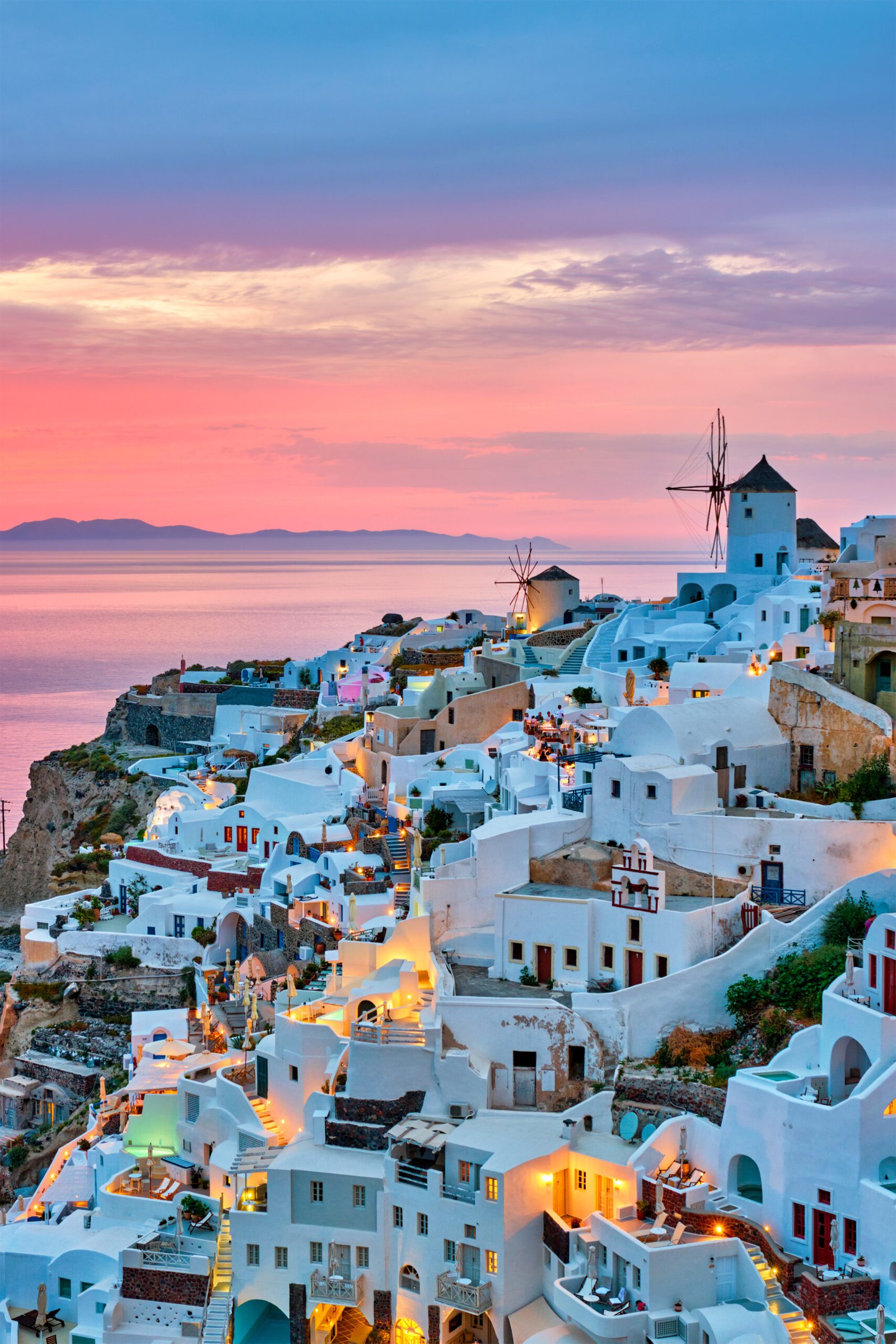 Famous greek iconic selfie spot tourist destination Oia village with traditional white houses and windmills in Santorini island on sunset in twilight, Greece