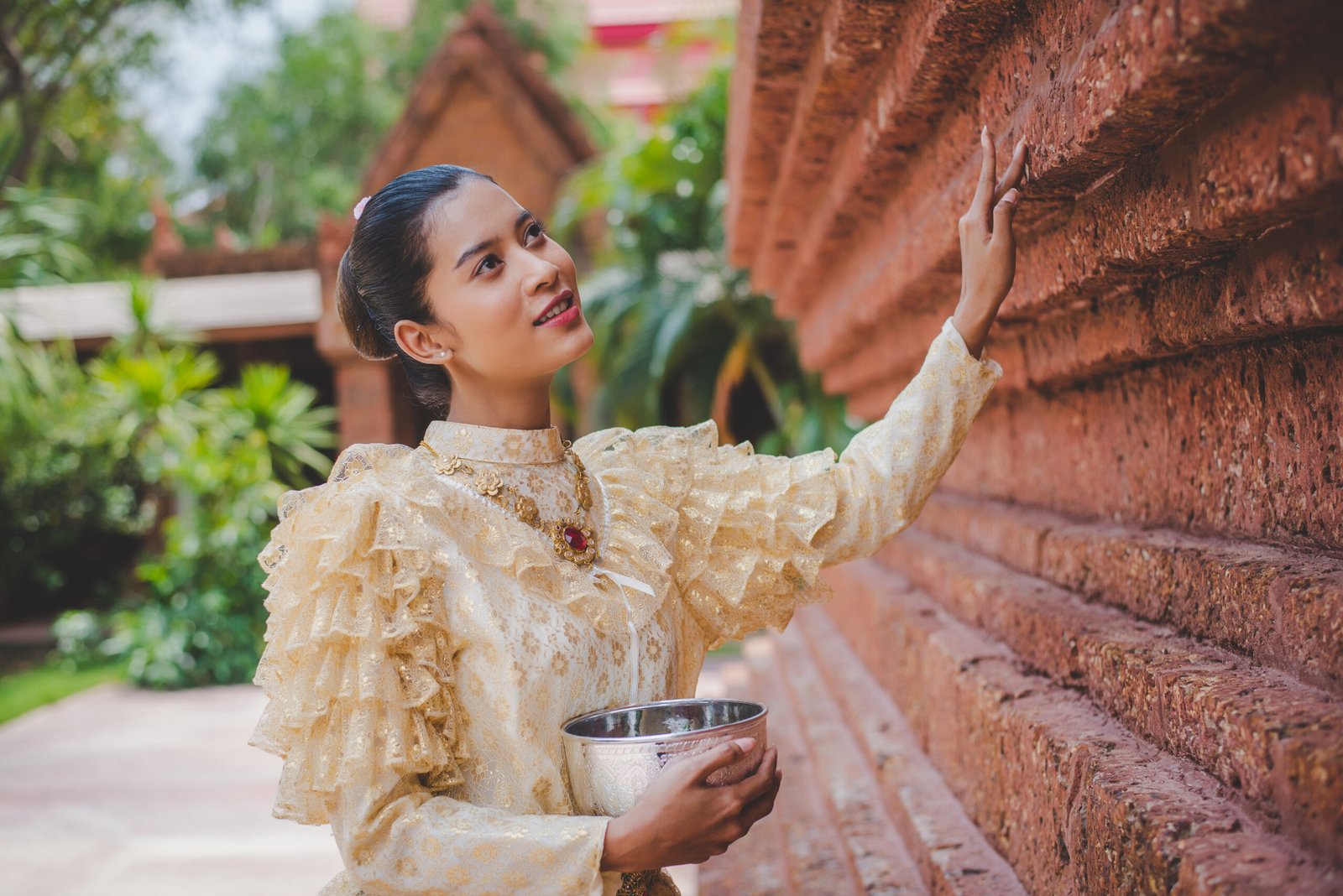 Portrait beautiful woman in Songkran festival with Thai Traditional costume in the temple holding water bowl and smile. Thailand culture with Water festival